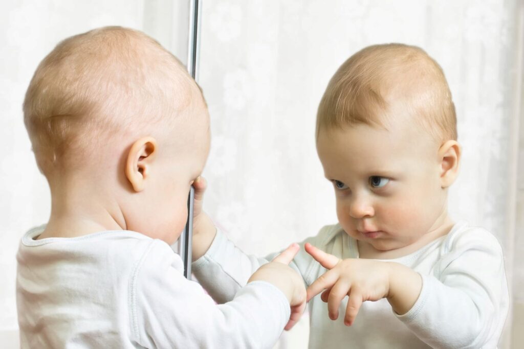 A baby looking at himself in a mirror