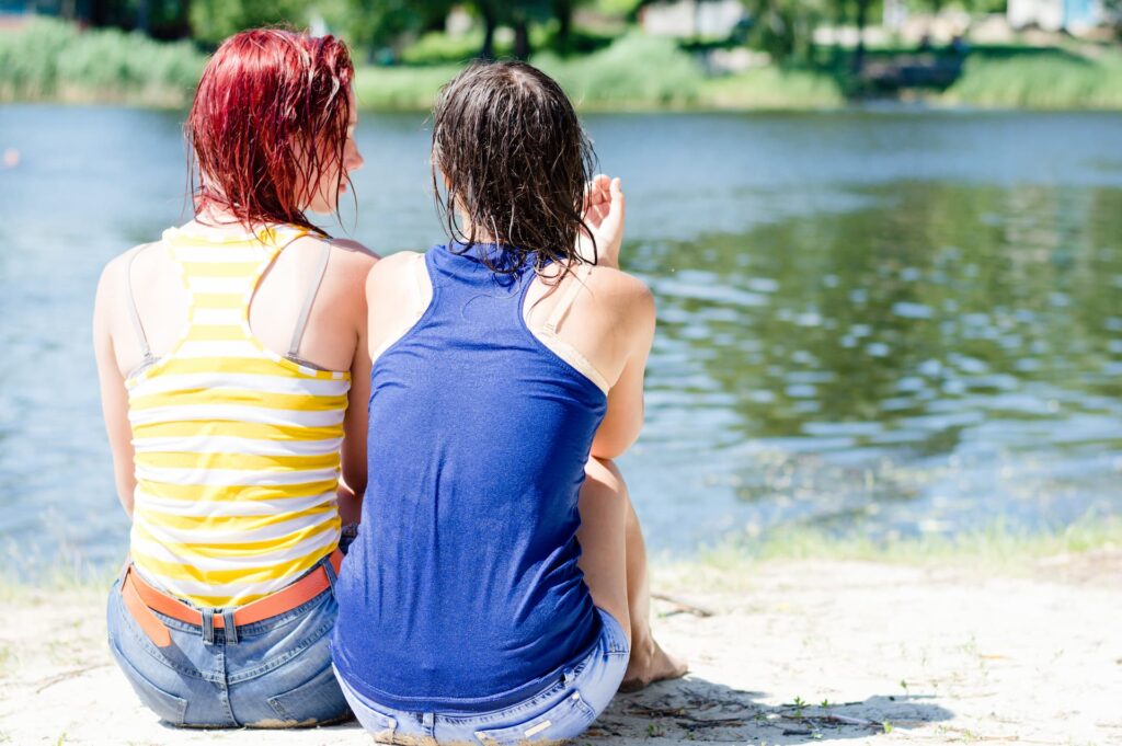 Two women sitting near a lake